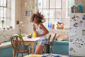 Happy curly haired girl dancing wearing pyjamas at home