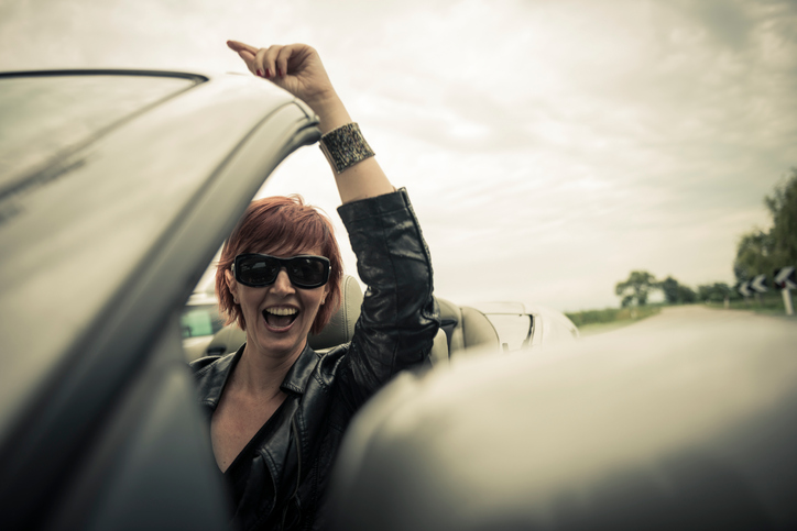 Excited woman enjoying driving her convertible car